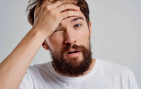 Emotionele man in een wit t-shirt hoofdpijn migraine problemen lichte achtergrond — Stockfoto