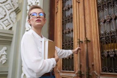 Açık havada elinde kitap olan kısa saçlı bir kadın. 