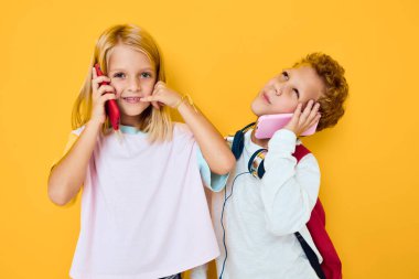 Okul çantalı iki kız ve erkek çocuk. Telefon eğlencesi.