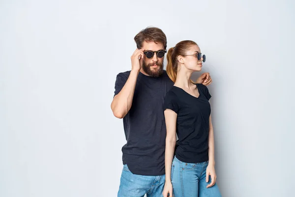 a young couple in black t-shirt sunglasses posing light background. High quality photo