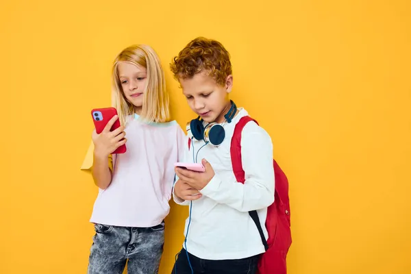 Zwei Kinder Junge und Mädchen mit Schulrucksäcken Telefon Unterhaltung Kommunikation Studio Bildungskonzept — Stockfoto