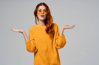 Sarı gözlüklü kızıl saçlı kadın eğlenceli yaşam tarzı ışık arka planında poz veriyor