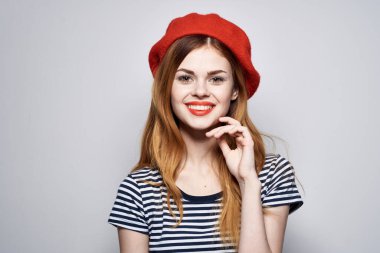 Kırmızı şapkalı neşeli Fransız kadın moda arkaplanı pozu veriyor.