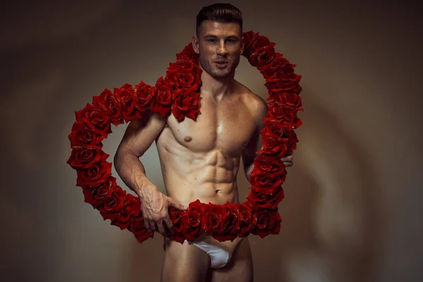 Un homme avec un corps nu pompé en culotte fleurs sous la forme d'un cadeau coeur — Photo
