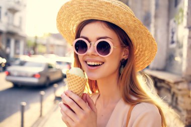 Güzel bir kadın dışarıda yürüyor ve dondurma yiyor.