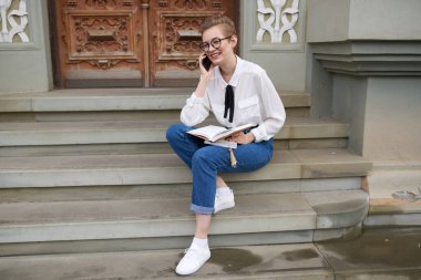 Gözlüklü güzel bir kadın şehirde dolaşıyor. 