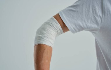 Beyaz tişörtlü, elleri bandajlı, izole edilmiş bir erkek hasta.