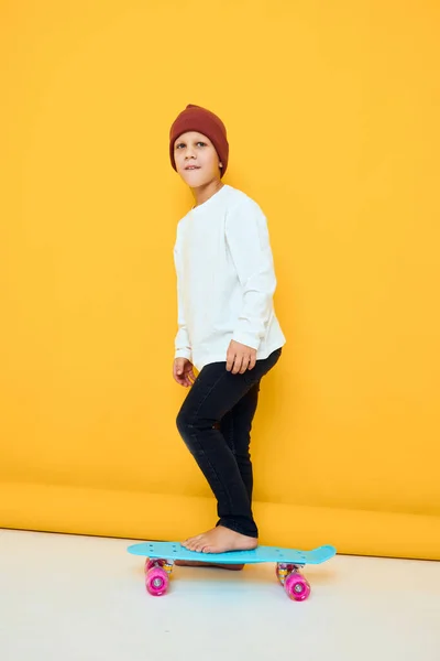 白いセーターでクールな笑顔男の子スケートボードエンターテイメントスタジオポージング — ストック写真