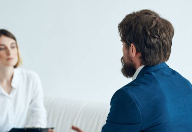 Kanepede oturan kadın ve erkek iş arkadaşlarıyla konuşuyor.