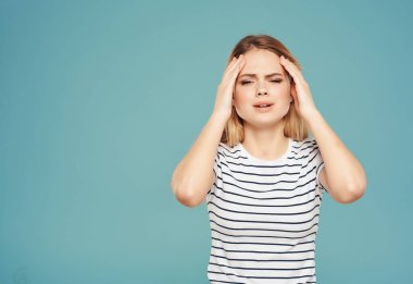 Yüzünde çizgili tişört teneke tabağı ve elleri mavi arka planı olan kızgın bir kadın.