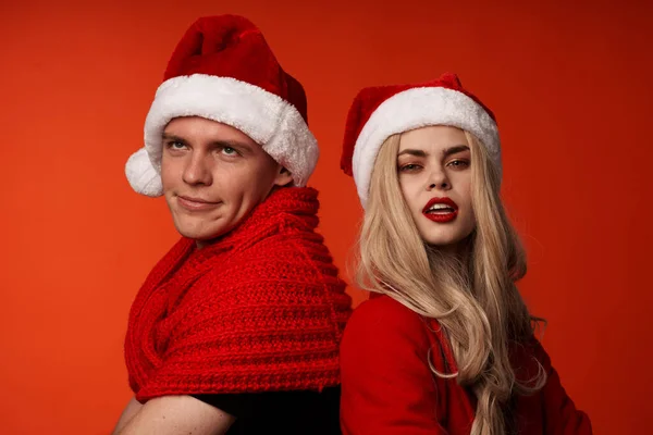 Jovem casal em santa chapéus divertido ano novo feriado fundo vermelho — Fotografia de Stock