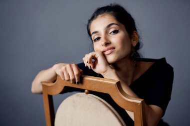 Güzel bir kadın, siyah elbiseli bir hayat stüdyosunda takı takıyor.