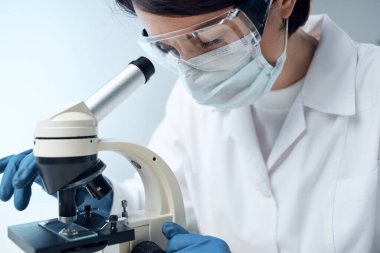 Laboratuvar asistanı, mikroskop araştırma biyoteknolojisi yakın planında oturuyor.