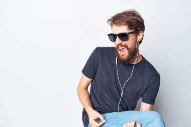 Siyah tişörtlü sakallı bir adam kulaklık takıyor, arka planda izole edilmiş.