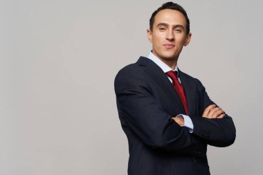 Klasik takım elbiseli bir iş adamı sahada kollarını göğsünde kavuşturdu.