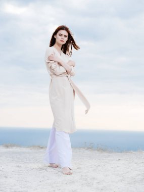 Kumsalda poz veren ceketli çekici kadın. Temiz hava yaşam tarzı.