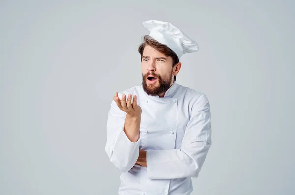 Vousatý muž kuchař uniforma vaření emoce světlo pozadí — Stock fotografie