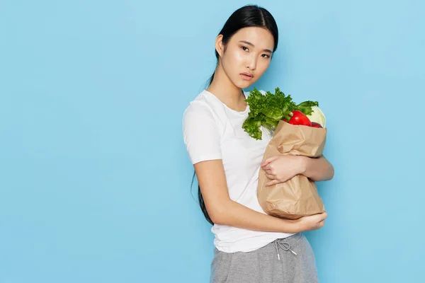 Mujer joven con un paquete de productos en un fondo azul dieta calorías estilo de vida saludable —  Fotos de Stock