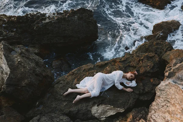 Barefoot woman in a white dress lying on a stone in a white dress nature — Stock Photo, Image