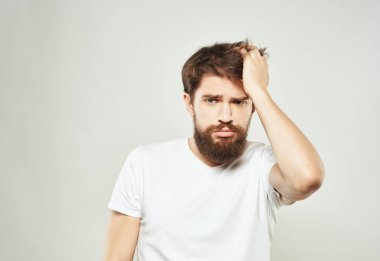 Beyaz tişörtlü sakallı bir adam. Elinde öfke ışığı arka planı var.