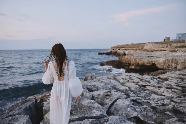 Beyaz elbiseli kadın okyanusa doğru yürür — Stok fotoğraf