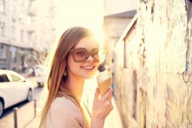 Sokakta yürüyen güneş gözlüklü neşeli bir kadın.