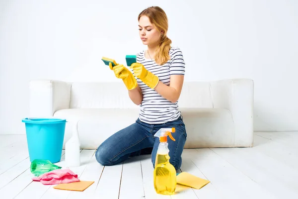 Limpieza mujer cerca del sofá detergente trapos esponjas prestación de servicios — Foto de Stock