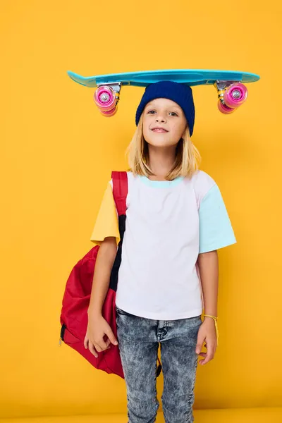 Skolflicka med en skateboard på huvudet isolerad bakgrund — Stockfoto