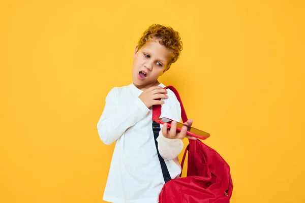 Fröhlicher Schüler mit rotem Rucksack telefoniert isoliert — Stockfoto