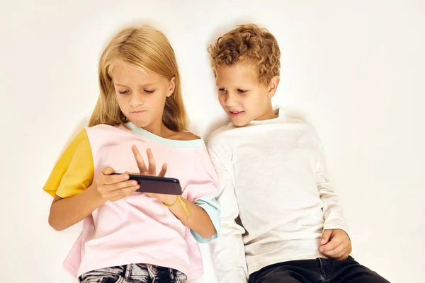 Junge mit Mädchentelefon in der Hand Spieltechnik — Stockfoto