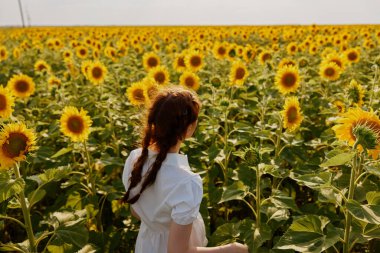 Beyaz elbiseli iki örgülü kadın doğaya hayrandır.