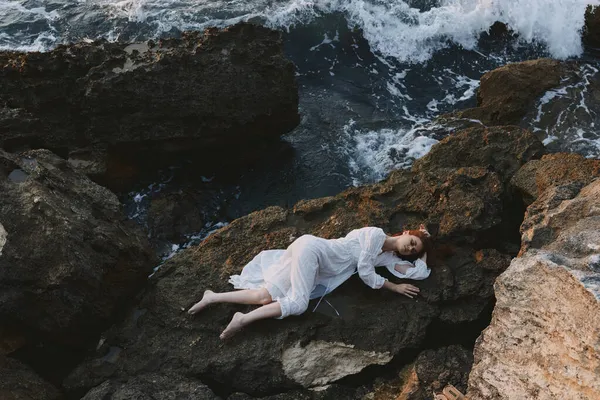 Vacker ung kvinna ligger på stenig kust med sprickor på stenig yta landskap — Stockfoto