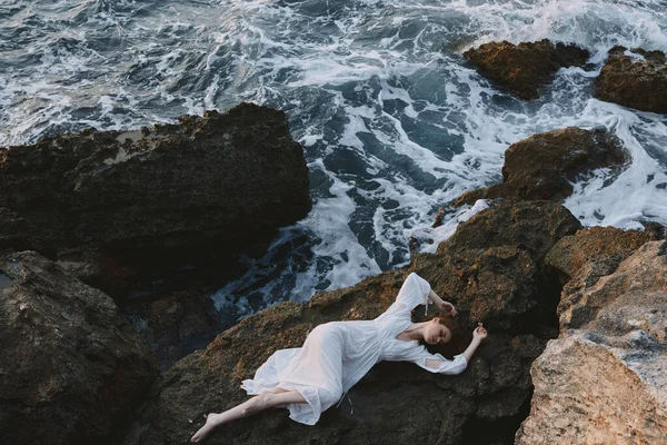 Woman lying on her back on a rocky seashore nature — Stock Photo, Image