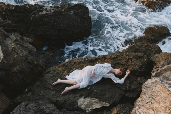 Barfota kvinna ligger på stenig kust med sprickor på stenig yta oförändrad — Stockfoto