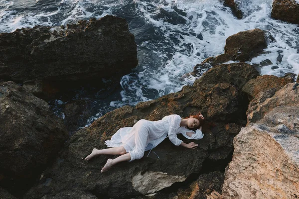 Woman in a white dress lying on a stone in a white dress Summer vacation concept — Stock Photo, Image