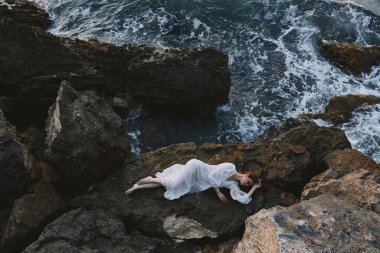 Deniz kıyısında beyaz gelinlikli güzel bir kadın. Islak saçlı, değişmemiş.