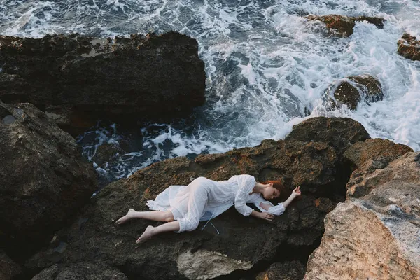 Beautiful bride lying on her back on a rocky seashore Summer vacation concept — Stock Photo, Image