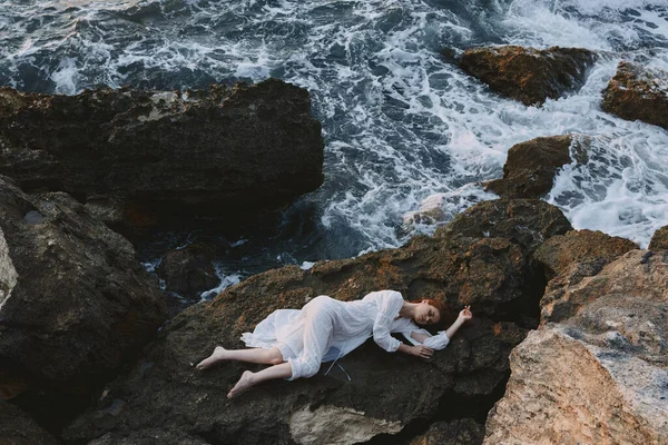 Kvinna liggande på rygg på en stenig kust natur — Stockfoto