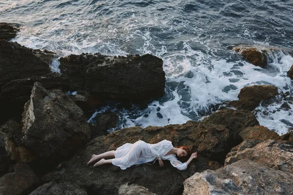 美丽的新娘躺在岩石海岸上，从上面俯瞰岩石表面的裂缝 — 图库照片