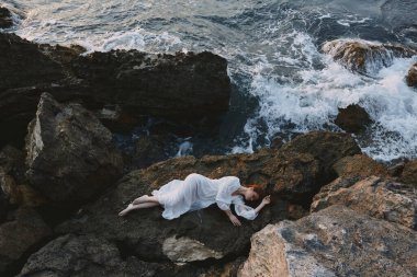 Güzel gelin kayalık sahilde yatıyor kayalık yüzey manzarasında çatlaklar var