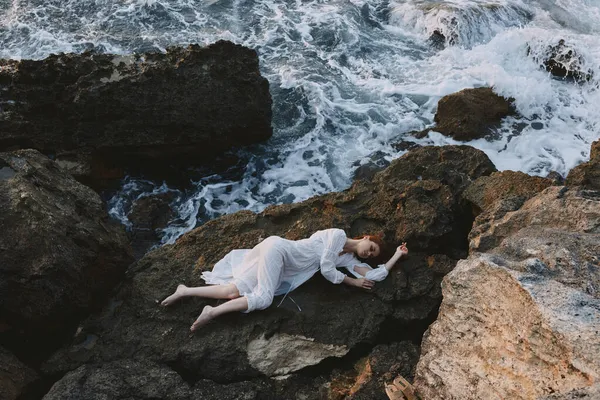 Vacker brud i en avskild plats på en vild stenig kust i en vit klänning landskap — Stockfoto
