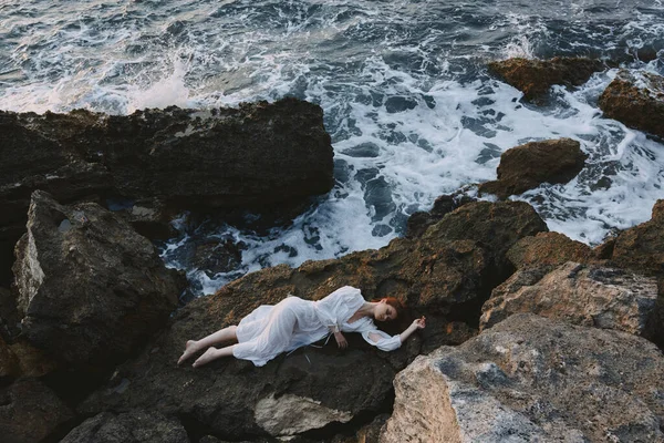 Schöne Braut liegt an felsiger Küste mit Rissen auf felsiger Oberfläche Urlaubskonzept — Stockfoto