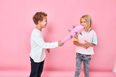 Oğlan bir kıza oyuncak sopa gösteriyor.