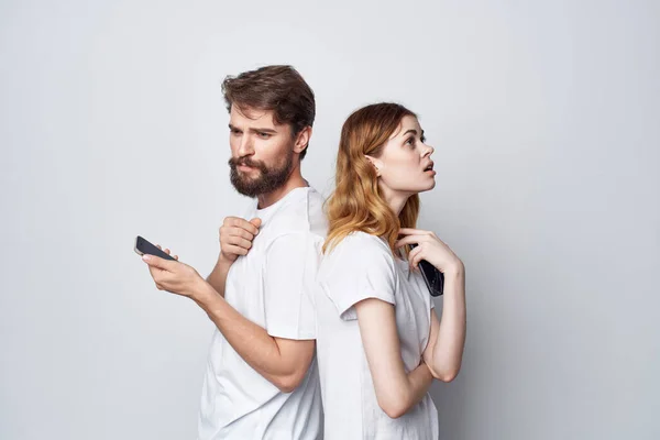 携帯電話を手にした白いTシャツの男と女たちのスタジオライフスタイル — ストック写真