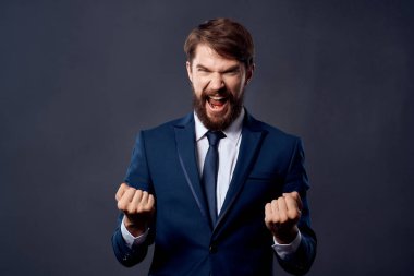 Takım elbiseli sakallı iş adamı duygularıyla el kol hareketi yapıyor.