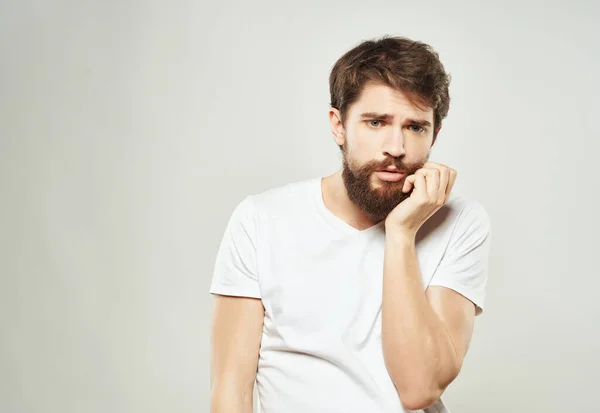 Bearded man in a white t-shirt irritated facial expression Studio Stock Photo