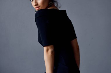 Güzel bir kadın takı takıyor. Siyah elbiseler giyiyor.