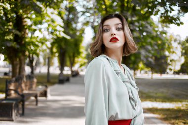 Neşeli kadın çekici görünüyor. Kırmızı dudaklar parkta yürüyor. Temiz hava.