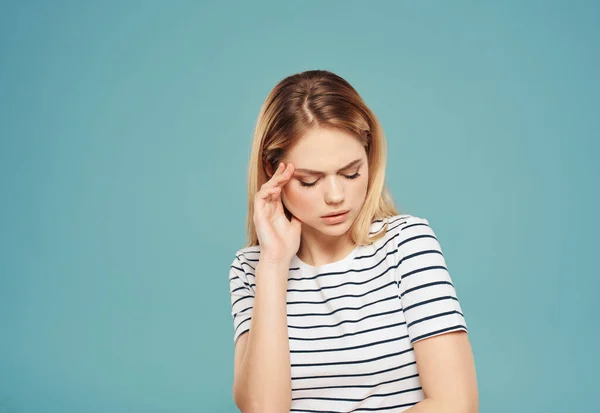 Triste mulher em listrado t-shirt segurando sua cabeça azul fundo — Fotografia de Stock