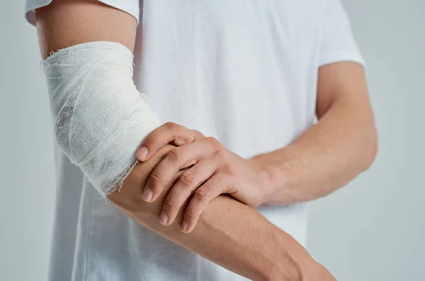 Hombre enfermo en una camiseta blanca con una medicina de hospital de mano vendada —  Fotos de Stock